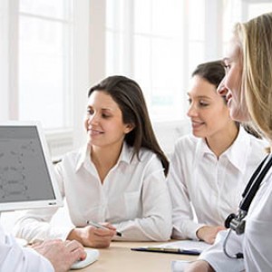 Photo of doctor with medical students looking at computer screen together.