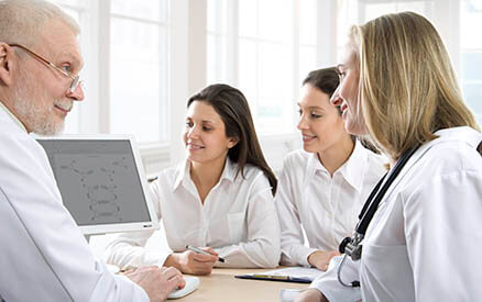 Photo of doctor with medical students looking at computer screen together.